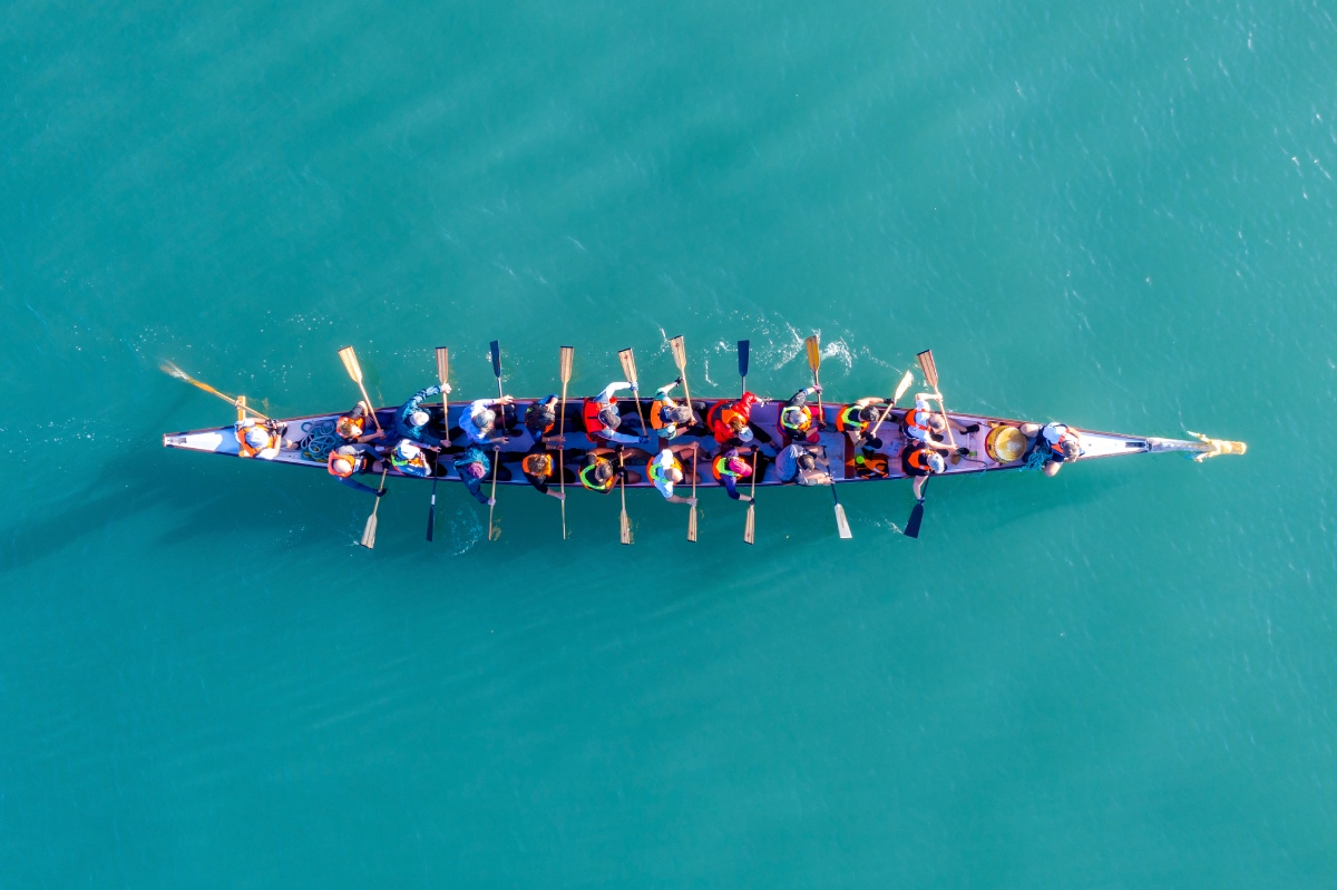 A diverse group of people paddling on a canoe in a serene lake